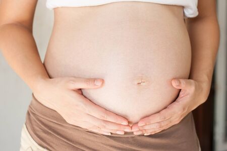 Pregnant woman holding her hand on bellyの写真素材
