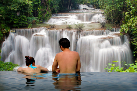 Man and Woman relaxing in Swimming pool and waterfall sceneの写真素材