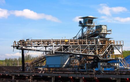 Large conveyor belt carrying coal and emptying onto a huge pile.の写真素材