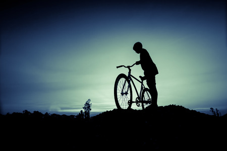 vintage effect style of silhouette of children and bicycle at sunset