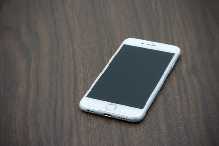 BANGKOK, THAILAND - MAY 7, 2015. Apple Iphone 6 in white color with blank screen laying on wooden table.のeditorial素材