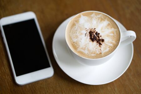 Cup of mocha coffee and smart phone on the tableの写真素材