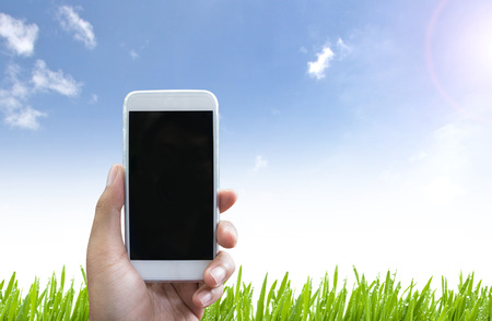 Man's hand shows mobile smart phone in vertical position and Nature background - mockup templateの写真素材