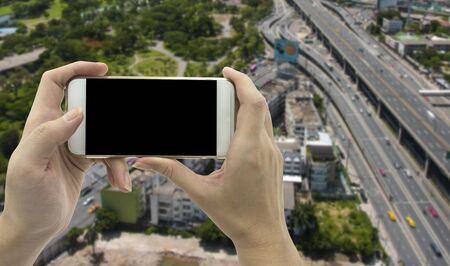 Female Hand holding smart phone over traffic road background - mockup templateの写真素材