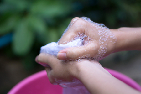 Female Hand washing clothes in the pink basin.の写真素材