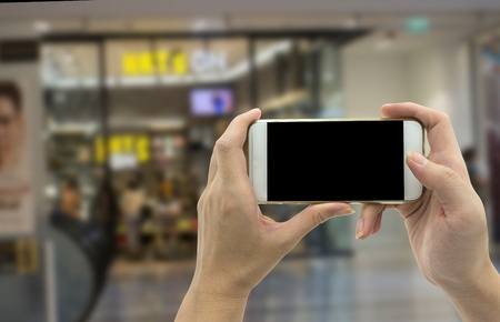 Woman hand shows mobile smartphone and blurred background - mockup templateの写真素材