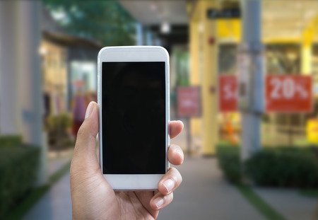 Man's hand shows mobile smartphone in vertical position, blurred background - mockup templateの写真素材