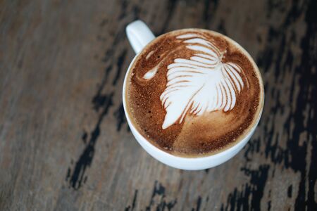 coffee latte art on the wooden desk - vintage filter effectの写真素材