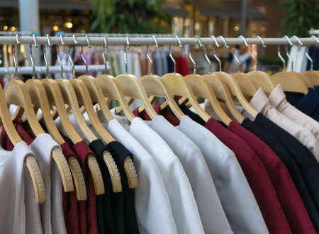 Women clothes hanging on wooden hangers in a storeの写真素材