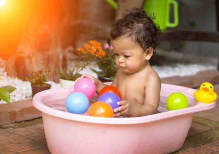 Asian baby Bathing in tubs and Asian baby enjoyed playing with colored balls. - Sunlight filter effect.の写真素材