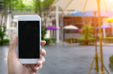 Man's hand shows mobile smartphone in vertical position, blurred background - mockup templateの写真素材