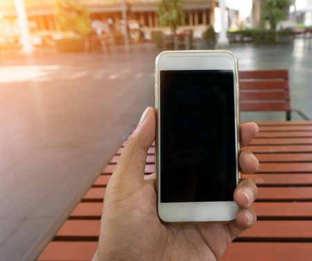 Man's hand shows mobile smartphone in vertical position, mockup template with blurred background -  Sunset filter effectの写真素材