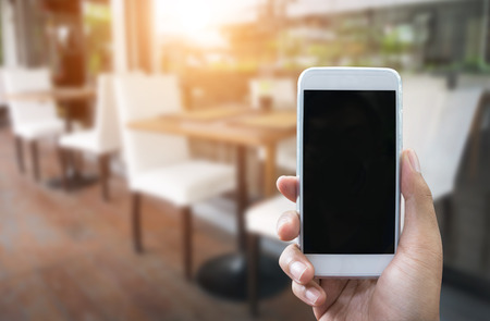 Man's hand shows mobile smartphone in vertical position and blurred background - smartphone mockup templateの写真素材
