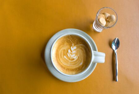 Cup of latte coffee on yellow Leather table - Top view , latte art coffee in a relax timeの写真素材