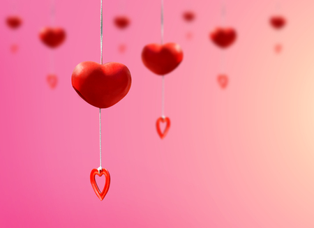 Red heart mobile made from ceramic clay hanging on pink background for valentine's day concept design.の写真素材