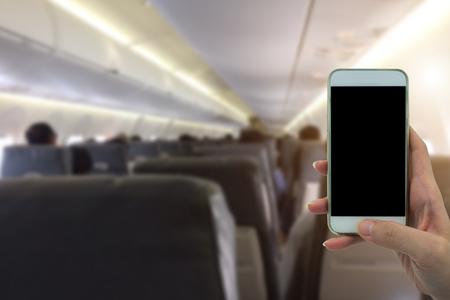 Woman use your phone in airplane blurred background - mockup template - sunlight filter effectの写真素材