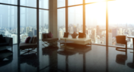 Blured of Modern sofa and building glass on tower in living room with urban skyline building background and warm sunlight in afternoon time.の写真素材