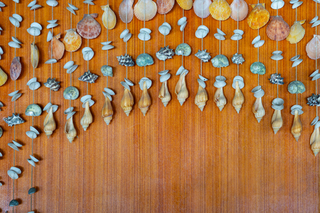 Summer concept background with seashells hanging mobile on a brown wooden.の写真素材