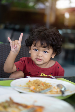 Curly hair asian child concede and eating breakfast in a restaurant.の写真素材