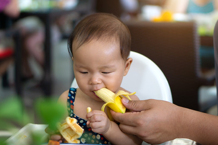 Cute asian toddler baby girl eating banana.の写真素材