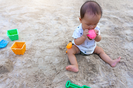 Asian toddler baby thai girl playing with sand in the playground.の写真素材