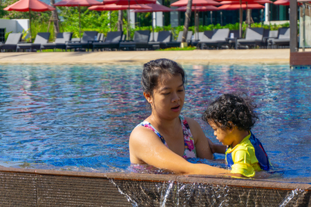 Asian child boy learn swimming in a swimming pool with mom.の写真素材