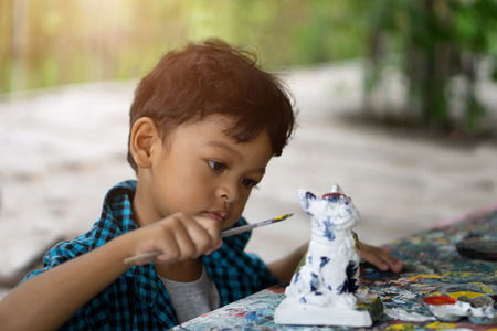 Asian kids enjoying his painting with paintbrush.の写真素材