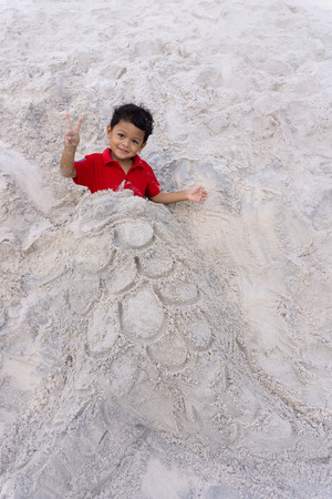 Asian family son and Mother play Buried in the sand on the beach.の写真素材