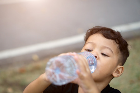 Asian thai kids drink water in park.の写真素材