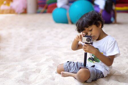Asian boy using action camera to take a picture or video.