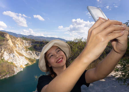 Asian female tourists are taking pictures of themselves at tourist attractions using a smartphone.の写真素材