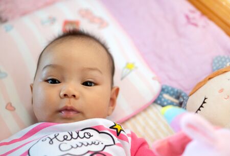 A 6 month old Asian girl is smiling and looking at his mother.