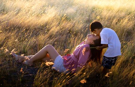 The son showed love for his mother. By kissing on the forehead of the mother at the meadow in the eveningの写真素材