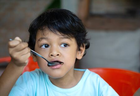 Asian boy is eating brownies during the day time.の写真素材
