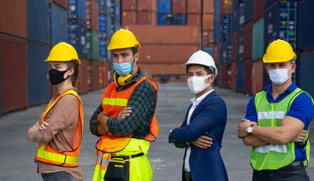 Industrial workers or engineers wearing Coronavirus or COVID-19 protective masks stand in front of the shipping container.の写真素材