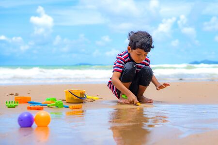Little asian boy play with toy and sand on the beach.の写真素材