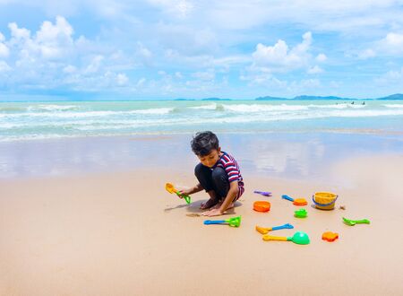 Little asian boy play with toy and sand on the beach.の写真素材