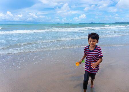 Asian kid play running in the sea and enjoying life during the summer holidays on the Phala Beach, Ban Chang District, Rayong, Thailand.の写真素材