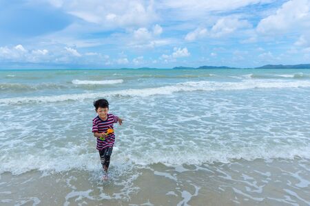 Asian kid enjoy playing in the sea and enjoying life during the summer holidays on the beach.の写真素材