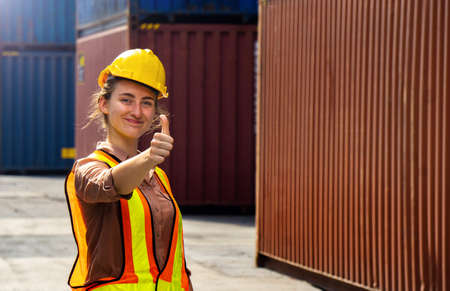 Industrial women give a thumbs up on the container background in the import and export business