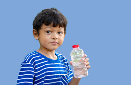 Asian kid thirsty water and hold transparent plastic water bottle water in the park.の写真素材