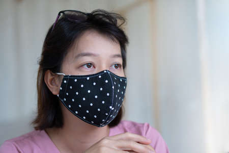 Asian woman wearing protective mask on her face while being in the coffee shop during virus COVID-19 pandemic.の写真素材