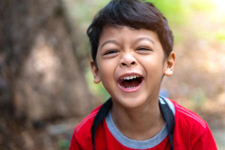 A boy wearing a red shirt laughed happilyの写真素材
