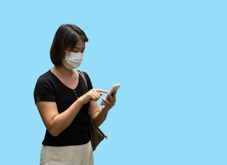 Young asian woman using smartphone and wearing face mask protect Coronavirus (COVID-19) for Health care conceptの写真素材