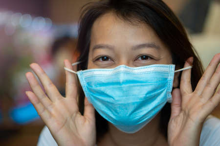 Asian woman wearing protective mask on her face while being in the coffee shop during virus COVID-19 pandemic.の写真素材