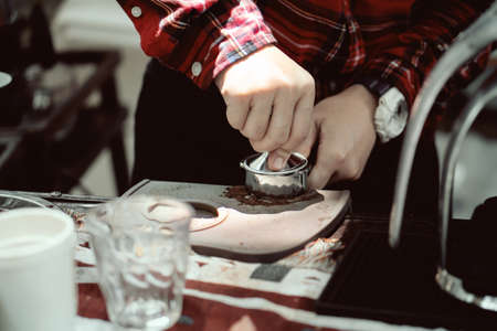 The barista presses the ground coffee to make espresso.の写真素材