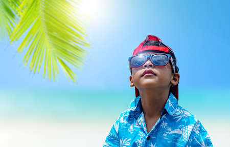 An Asian boys wear sunglasses and summer clothes on a bright summer sea background.の写真素材