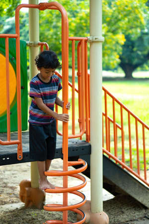 An Asian boy is climbing on a playground equipment in a school.の写真素材