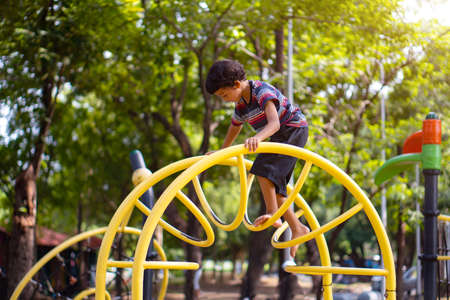 An Asian boy is climbing on a playground equipment in a school.の写真素材