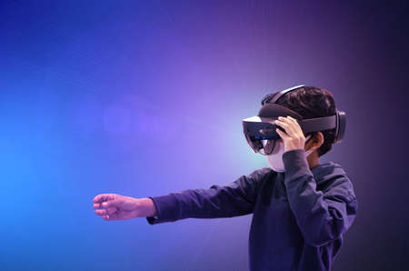 Asian kid boy using metaverse VR virtual reality glasses to digital technology metaverse game.